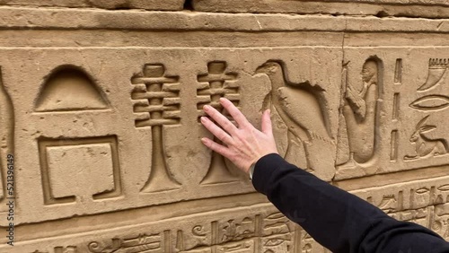  A woman hand touching an Egyptian hieroglyph carved in stone photo