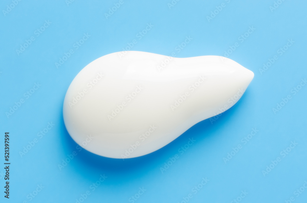 A sample of white moisturizer on a blue background. Cosmetic product for the skin. A sample of white moisturizer on a blue background. Cosmetic product for the skin.