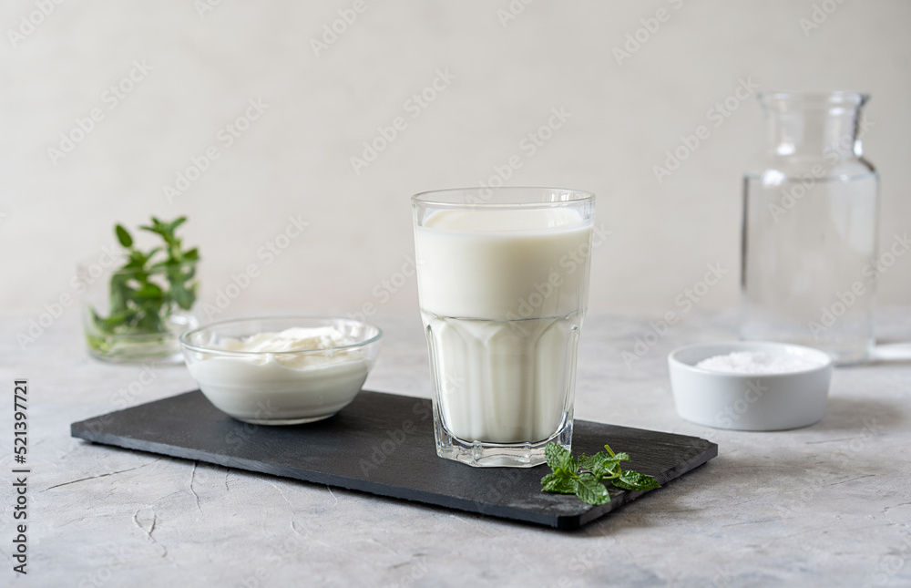 Ayran or Doogh is a popular refreshing Middle Eastern beverage made with yogurt, water and salt. Concrete background Ayran or Doogh is a popular refreshing Middle Eastern beverage made with yogurt, water and salt. Concrete background