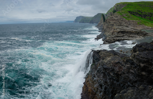 Bosdalafossur waterfall to ocean on Vagar island coastline, Faroe Islands photo