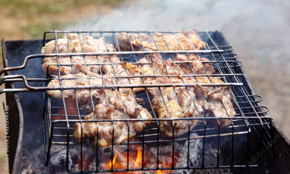 Tasty chicken wings cooking on barbecue grill, outdoors. Roasted chicken meat, closeup
