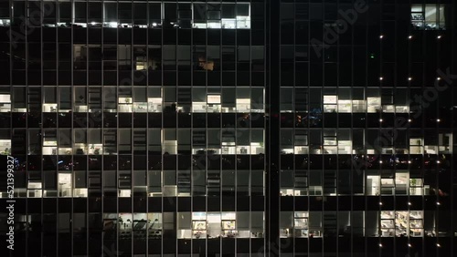 Office buildings with lights in the city downtown. Drone aerial view. People working in office building in the night, building lights in the night .  Economy business cityscape concept b-roll footage.