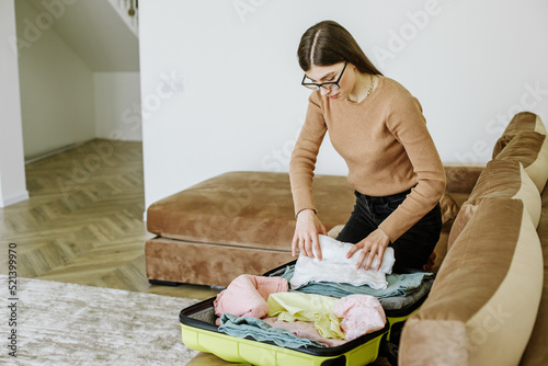 Happy young woman packing travel suitcase at home. Vacation preparation. Tourist trip.