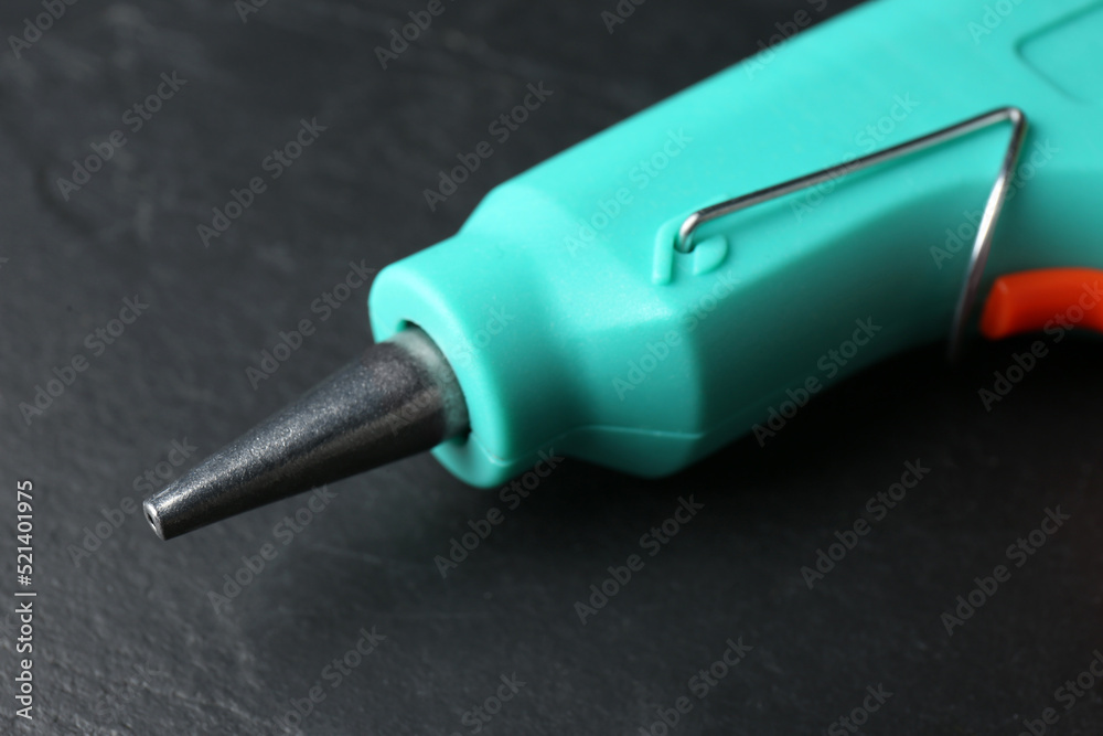 Hot glue gun on dark grey table, closeup Hot glue gun on dark grey table, closeup