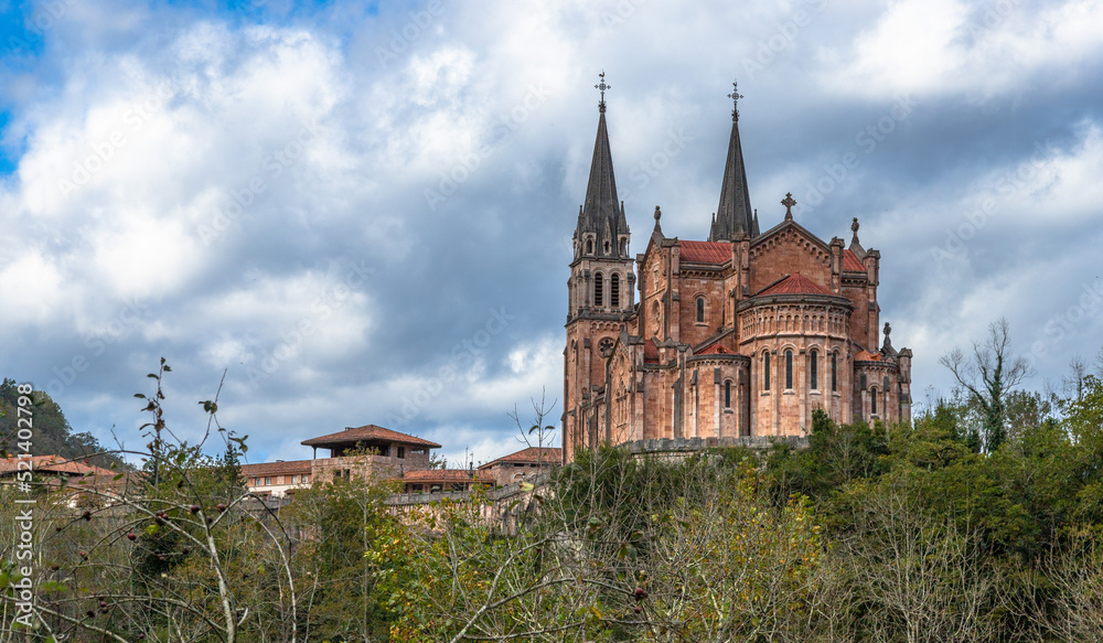 Fototapeta premium Basílica de Santa María la Real de Covadonga. Low point view of this great monumental temple built from 1877 to 1901, with a neo-Romanesque style and is made of pinkish marble stone extracted from the