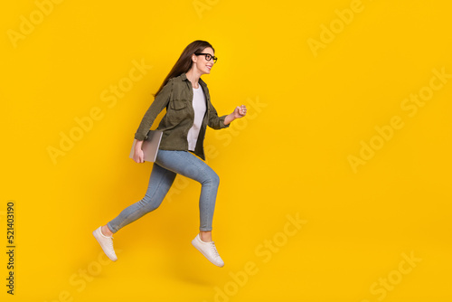 Full size profile side photo of attractive office worker girl jumping up run to workplace isolated on yellow color background © deagreez