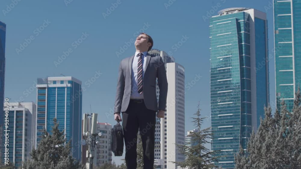 Nervous businessman running late, business buildings.
The business man in a suit with his bag in his hand looks at his watch and continues on his nervous way because he is late.
Nervous businessman running late, business buildings.
The business man in a suit with his bag in his hand looks at his watch and continues on his nervous way because he is late.