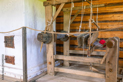 An old wooden loom made in the 19th century. A loom for fabric making in the room of a wooden village house built in the 19th century. The interior of a craftsman's house in the last century.