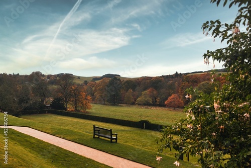 View of the empty bench surrounded by green lawns and autumn trees. Abbotsford House, Scotland. photo