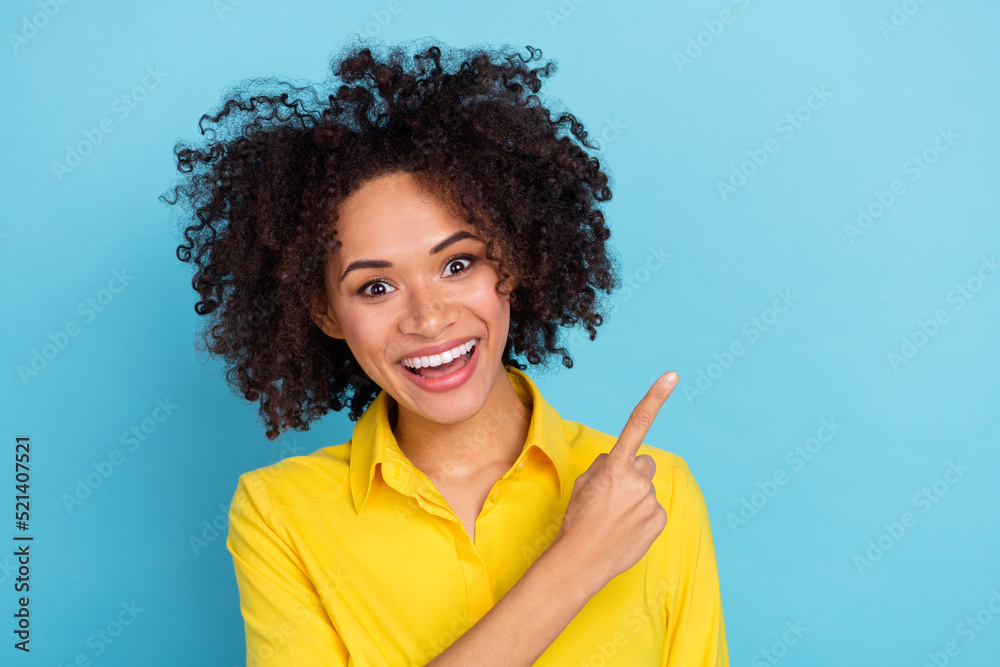 Photo of impressed curly hairdo young lady index empty space wear yellow blouse isolated on blue color background Photo of impressed curly hairdo young lady index empty space wear yellow blouse isolated on blue color background