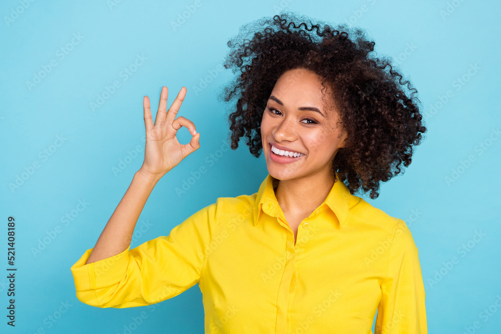 Photo of hooray curly hairdo young lady show okey wear yellow blouse isolated on blue color background Photo of hooray curly hairdo young lady show okey wear yellow blouse isolated on blue color background