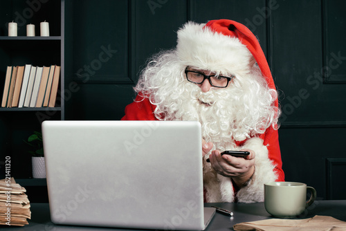 Santa Claus reads email. Saint Nicholas is working on a laptop.