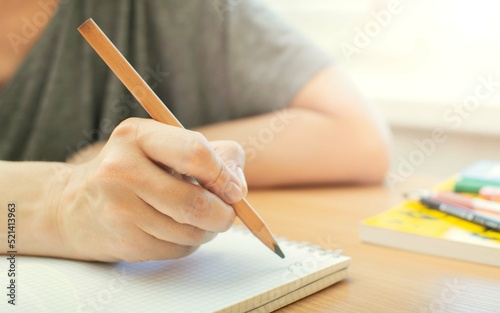 Close-up of a woman's hand making notes with a pencil in a notebook. Selective focus on the hand. Tinting. 