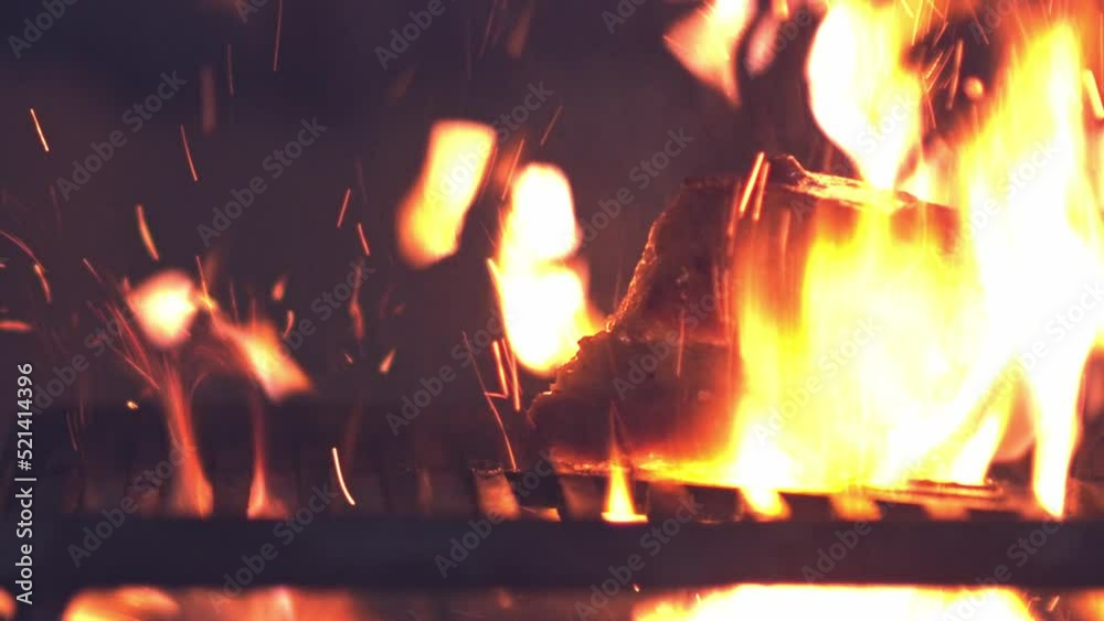 Pouring a burning alcohol based mixture on a thick cut of pork on a fire grill to sear it - slow motion