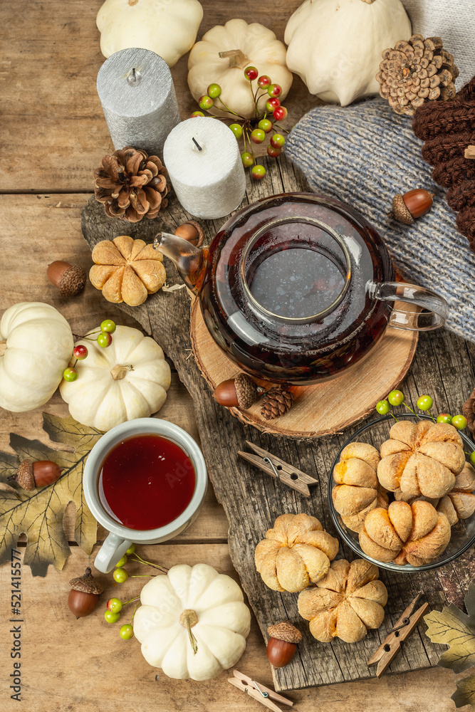 Autumn tea concept. Cookies with pumpkin puree, black tea in a glass teapot, fall decor Autumn tea concept. Cookies with pumpkin puree, black tea in a glass teapot, fall decor