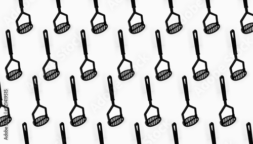 Фотография Pattern of black plastic potatoes masher on white background.
