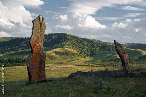 Tall stone menhir stands in hilly steppe. Safronovskie kurgans, Khakassia, Siberia, Russia photo