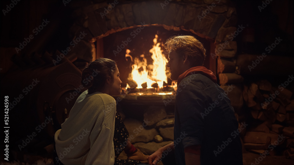Romantic couple sitting fireplace in country house. Two lovers enjoy cozy home.