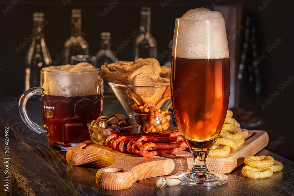 Glass of beer on bar counter, charcuterie plate board, meat, boiled pork, smoked meats, prosciutto. Jugs, mugs, pints of beverage, ale, cider, snack on wooden table in pub, bar in vintage brewery Glass of beer on bar counter, charcuterie plate board, meat, boiled pork, smoked meats, prosciutto. Jugs, mugs, pints of beverage, ale, cider, snack on wooden table in pub, bar in vintage brewery