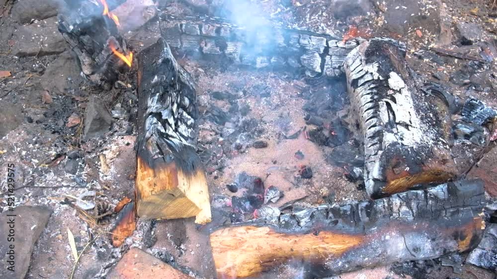 A man pushes the coals apart with a stake to bake potatoes A man pushes the coals apart with a stake to bake potatoes