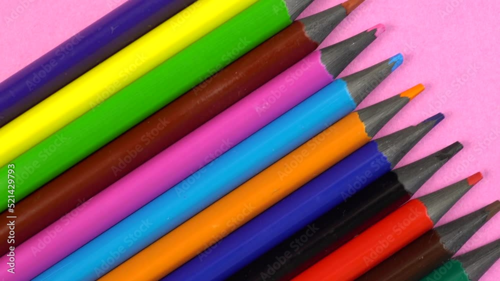 Slide shot of a set of colored sharpened pencils. Slow macro dolly on a pink background. Slide shot of a set of colored sharpened pencils. Slow macro dolly on a pink background.