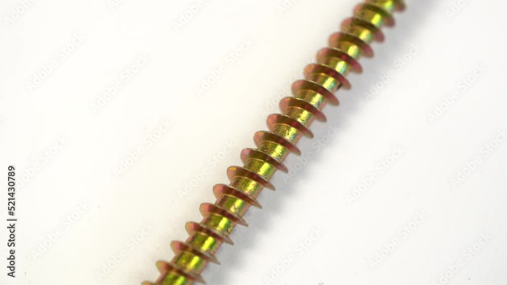 Golden screw 70 millimeters or 7 centimeters. Slide shot of a metal screw on a white background. Slow macro dolly screw. Metal industry concept. Golden screw 70 millimeters or 7 centimeters. Slide shot of a metal screw on a white background. Slow macro dolly screw. Metal industry concept.