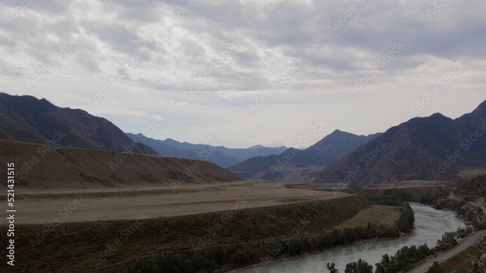 Mountains valley of Altai with blue Katun river under dramatic sky