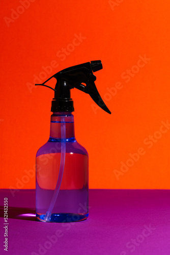 Isolated Transparent Sprayer Bottle on Vibrant Orange Background