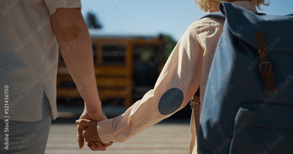 Obraz premium Mother holding son hand walking together to schoolbus sunny morning close up.