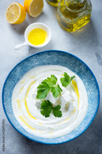 Plate with tirokafteri or greek feta dipping sauce, elevated view on a light-blue stone surface, vertical shot photo