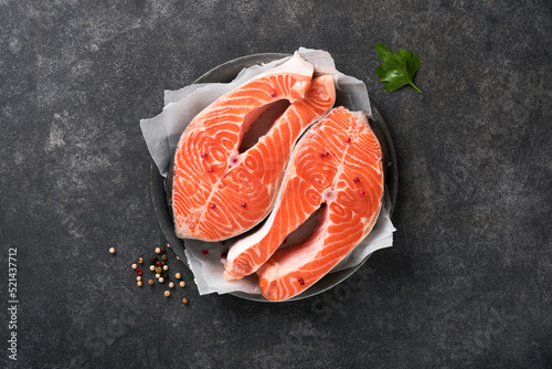Salmon. Raw salmon steak. Fresh raw salmon fish with cooking ingredients, herbs and lemon prepared for grilled baking on black background. Healthy food. Top view. Copy space.