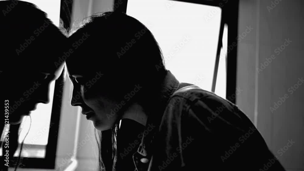 Depressed woman leaning on bathroom mirror reflection feeling sad and in distress. Monochromatic