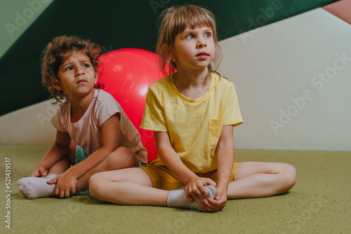 Little girls sitting near the exercise ball looking at camera