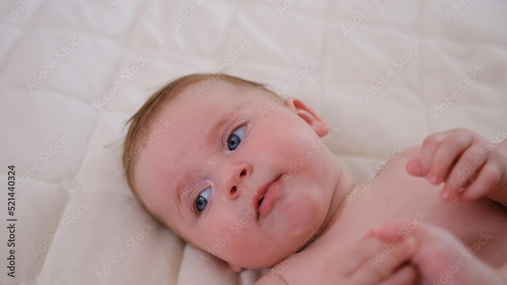 Portrait of a happy infant baby on the bed pulling his leg into his mouth, five months old. Laughing toddler kid on sofa, face close-up Portrait of a happy infant baby on the bed pulling his leg into his mouth, five months old. Laughing toddler kid on sofa, face close-up