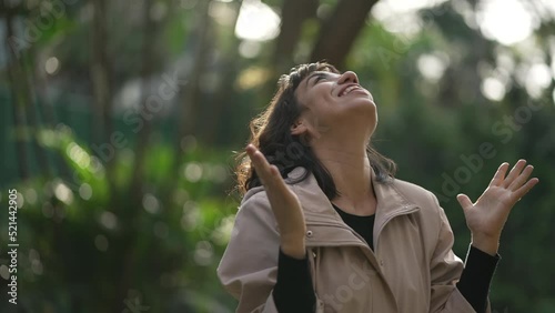 Evangelical South American woman standing outside feeling the presence of God arms in the air looking at sky with FAITH