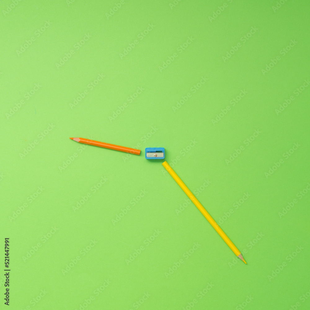 Two coloured pencils and sharpener in a shape of clock. Art and time concept. Two coloured pencils and sharpener in a shape of clock. Art and time concept.