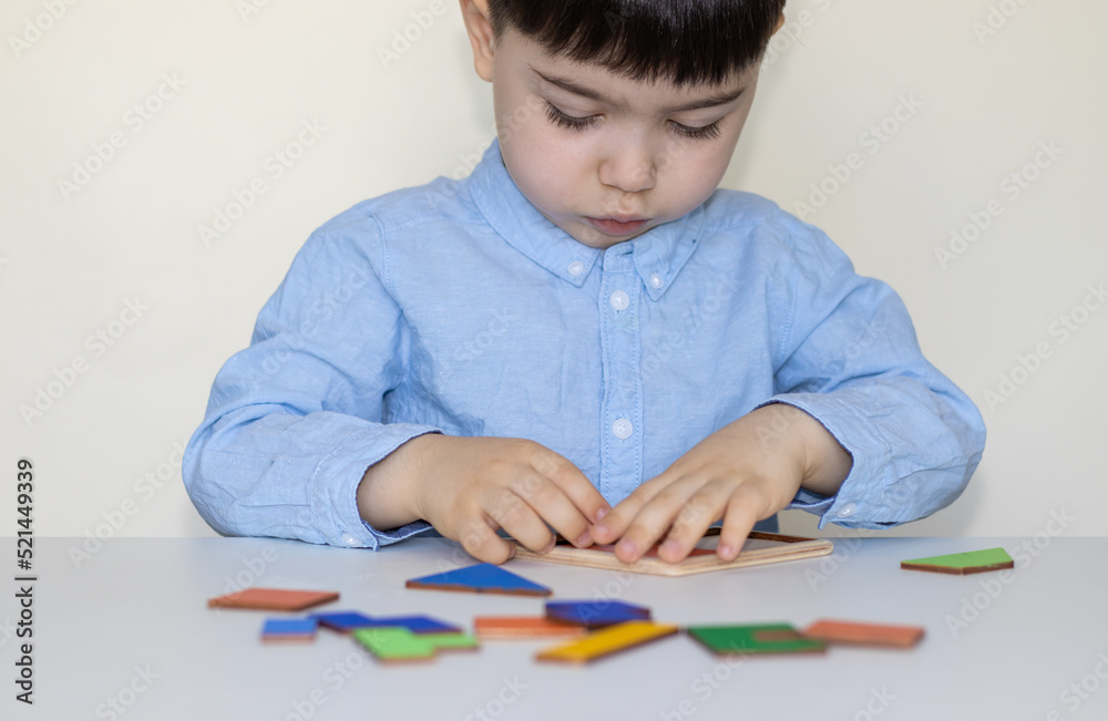 serious face baby boy playing tangram puzzle on school desk white table.isolated kid back to school kindergarten concept.high iq child smart kid.classroom home activities intellectual development serious face baby boy playing tangram puzzle on school desk white table.isolated kid back to school kindergarten concept.high iq child smart kid.classroom home activities intellectual development