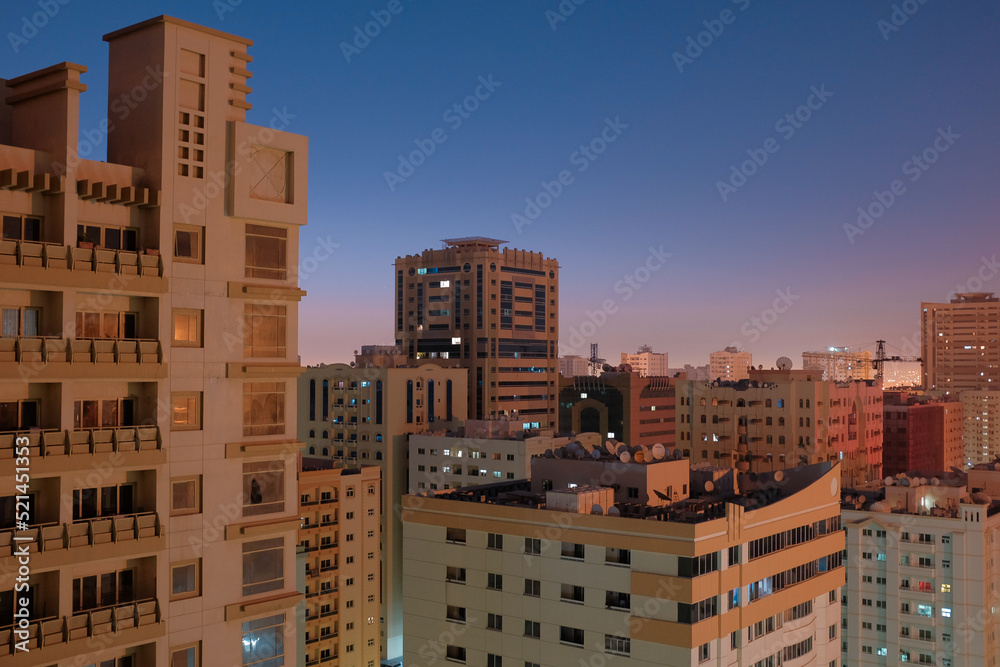 Balcony view of generic apartment buildings in the residential neighborhood of Al Qasimia in Sharjah, United Arab Emirates. Urban scene at dusk.
