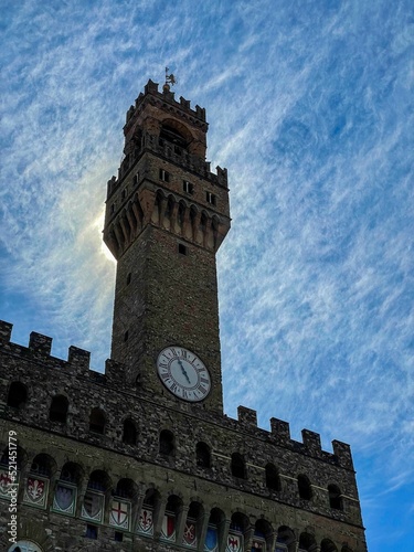 Vertical shot of the Arnolfo Tower against blue sky with fluffy clouds. Florence, Italy photo