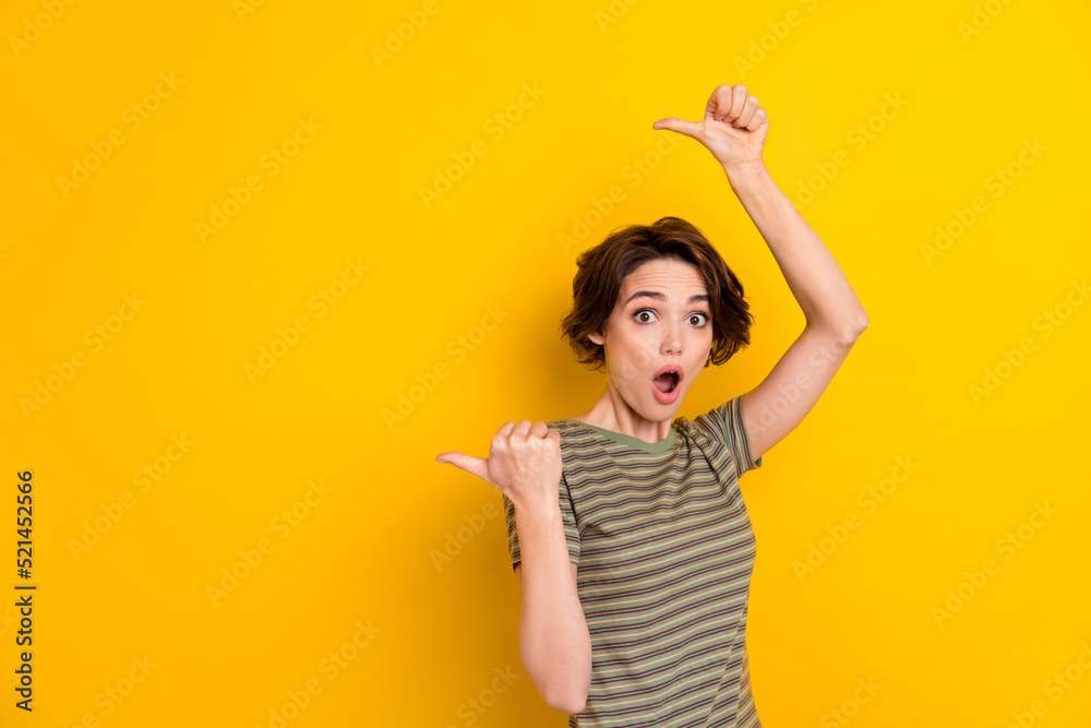 Photo of young attractive lady directing fingers empty space amazed crazy shopping deal isolated on bright yellow color background Photo of young attractive lady directing fingers empty space amazed crazy shopping deal isolated on bright yellow color background