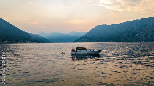 aerial view of boat in bay over the water during sunset with mountains on backgorund
