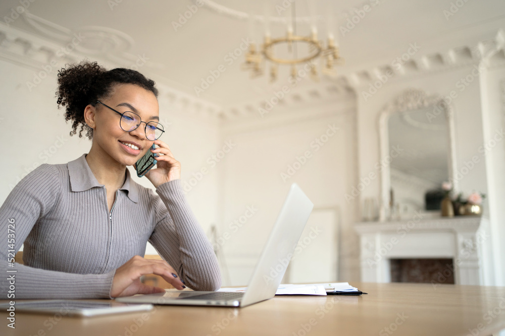 A freelancer woman works in an office coworking space, performs tasks using a laptop and a phone A freelancer woman works in an office coworking space, performs tasks using a laptop and a phone