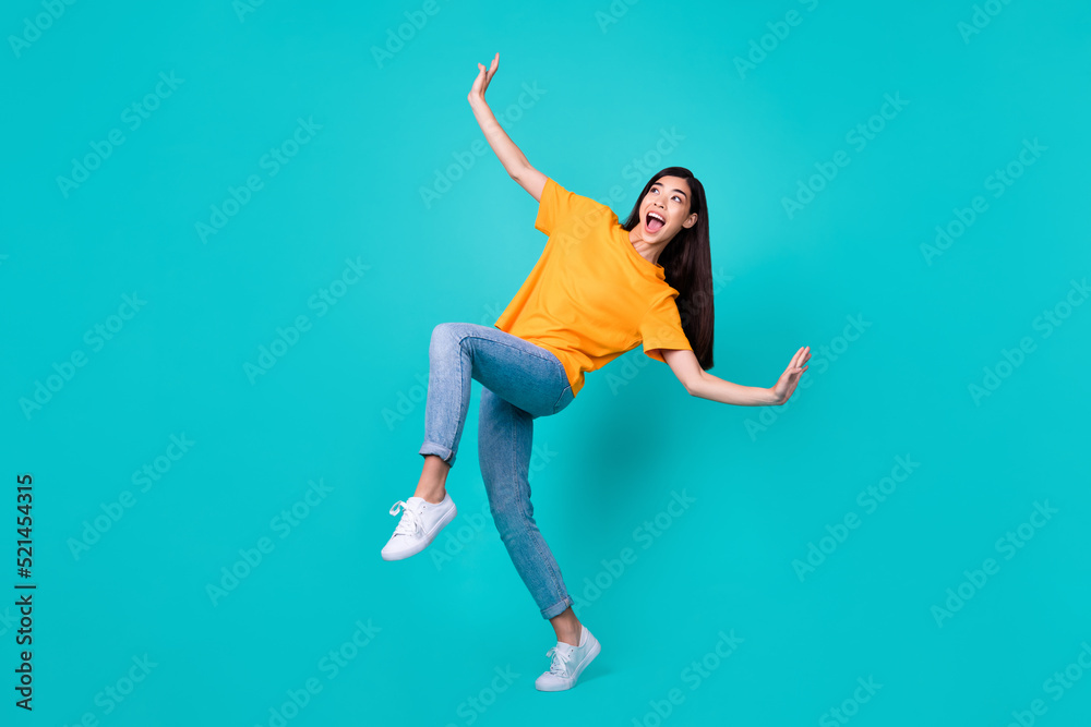 Full length photo of lovely brunette lady dance look up wear t-shirt jeans shoes isolated on teal color background