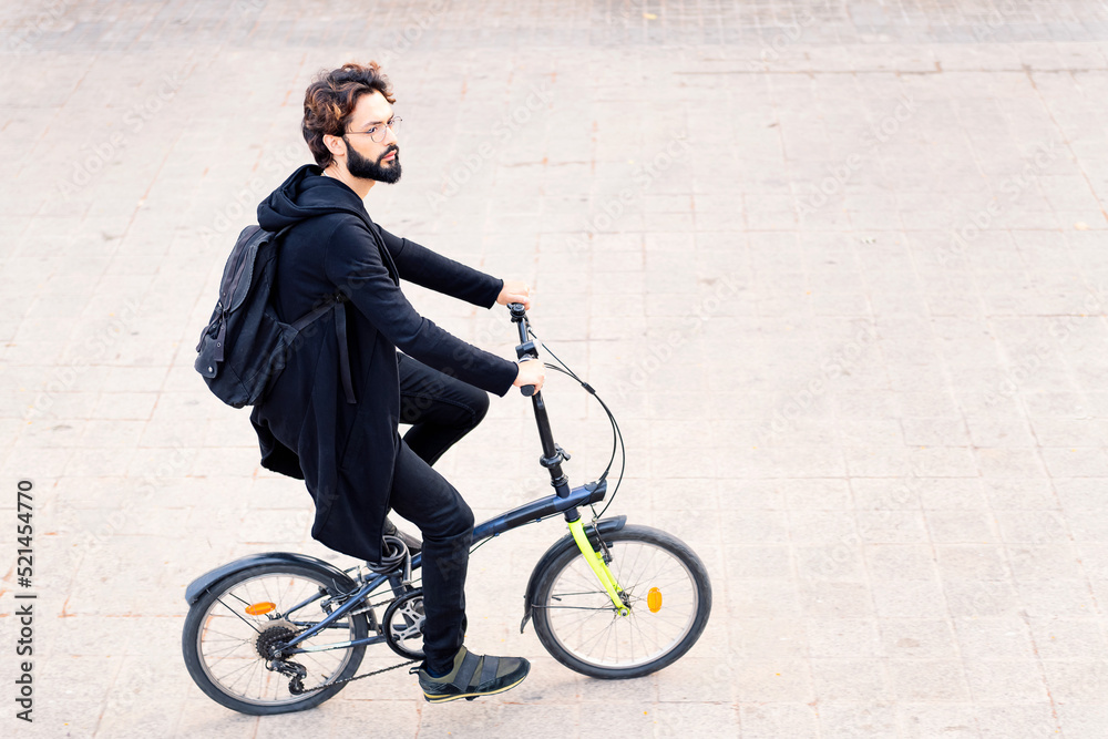 man wearing trendy clothes riding his folding bike