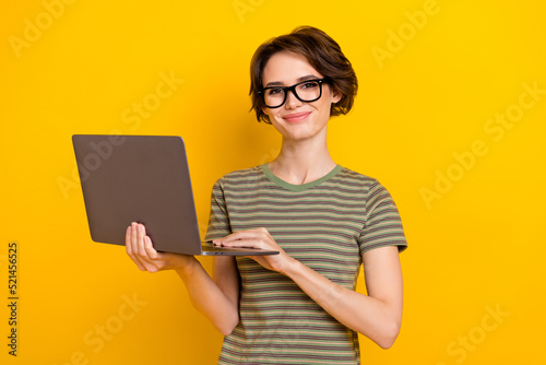 Photo of adorable cute lady wear striped t-shirt spectacles typing modern device isolated yellow color background