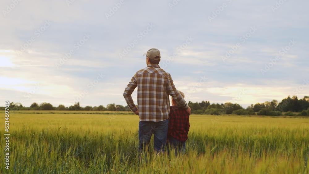 Farmer and his son in front of a sunset agricultural landscape. Man and a boy in a countryside field. Fatherhood, country life, farming and country lifestyle. Farmer and his son in front of a sunset agricultural landscape. Man and a boy in a countryside field. Fatherhood, country life, farming and country lifestyle.