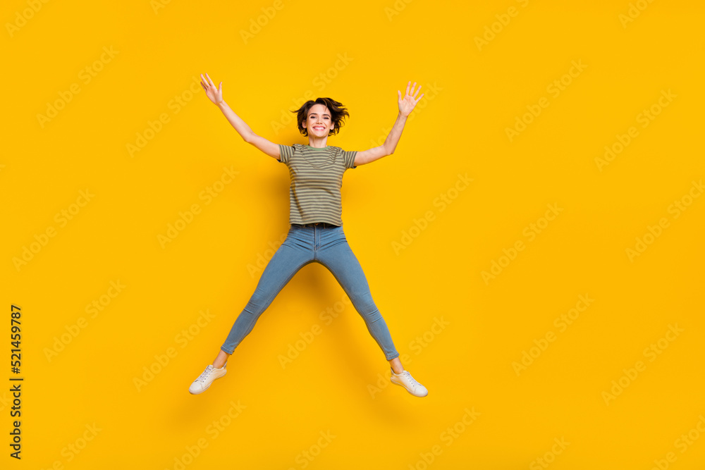 Full length photo of excited charming lady wear striped t-shirt jumping high empty space isolated yellow color background