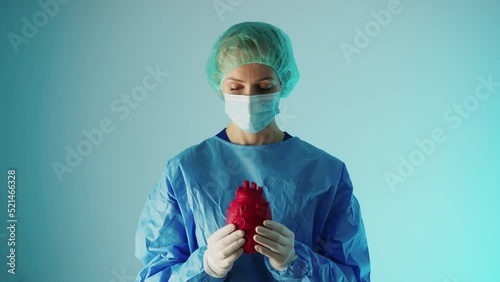 young caucasian surgeon holding a 3d artifficial heart model and showing it to the camera, cardiovascular diseases prevention. High quality 4k footage photo