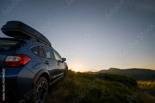 Blue offroad SUV car with roof trunk on background of very beautiful night starry sky after sunset. Freedom and travel by car concept