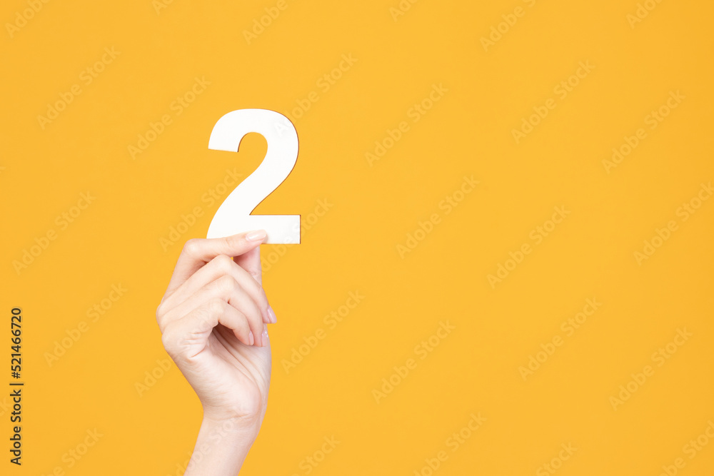 Hand holding wood number on yellow background. Hand holding wood number on yellow background.